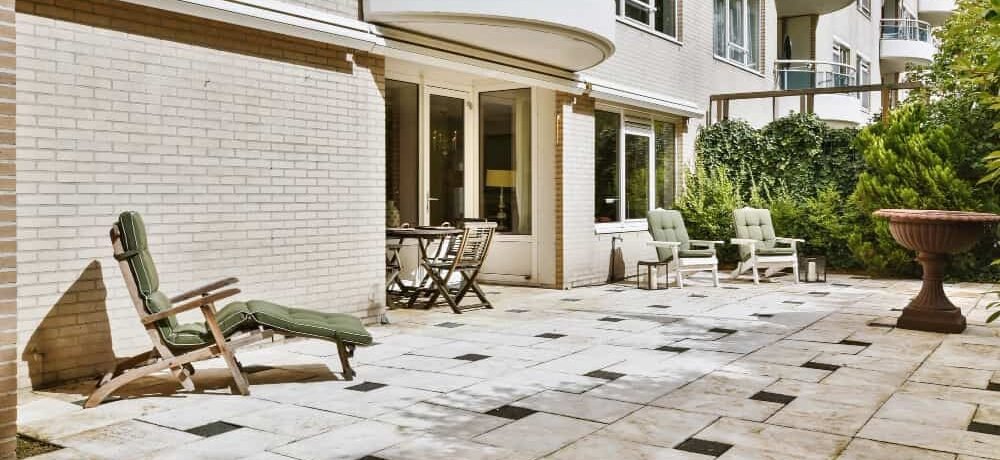 Grande terrasse en dalles de pierre claire agrémentée de cabochons noirs, un choix moderne de carrelage de terrasse et extérieur pour un immeuble résidentiel.