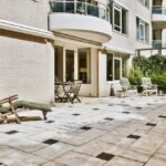 Grande terrasse en dalles de pierre claire agrémentée de cabochons noirs, un choix moderne de carrelage de terrasse et extérieur pour un immeuble résidentiel.